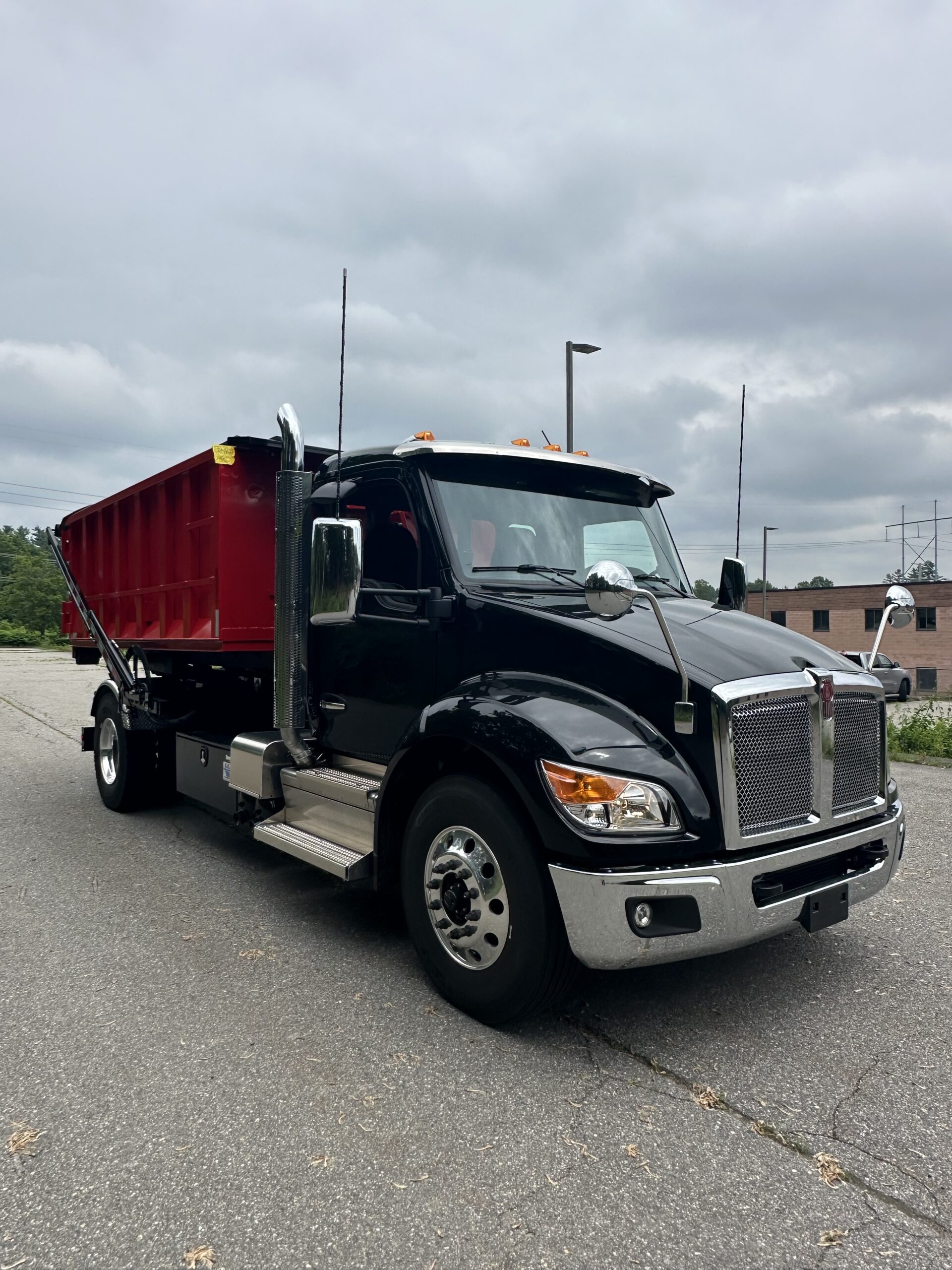 Branded Arsenal Waste Management roll-off truck on a job site in southern New Hampshire