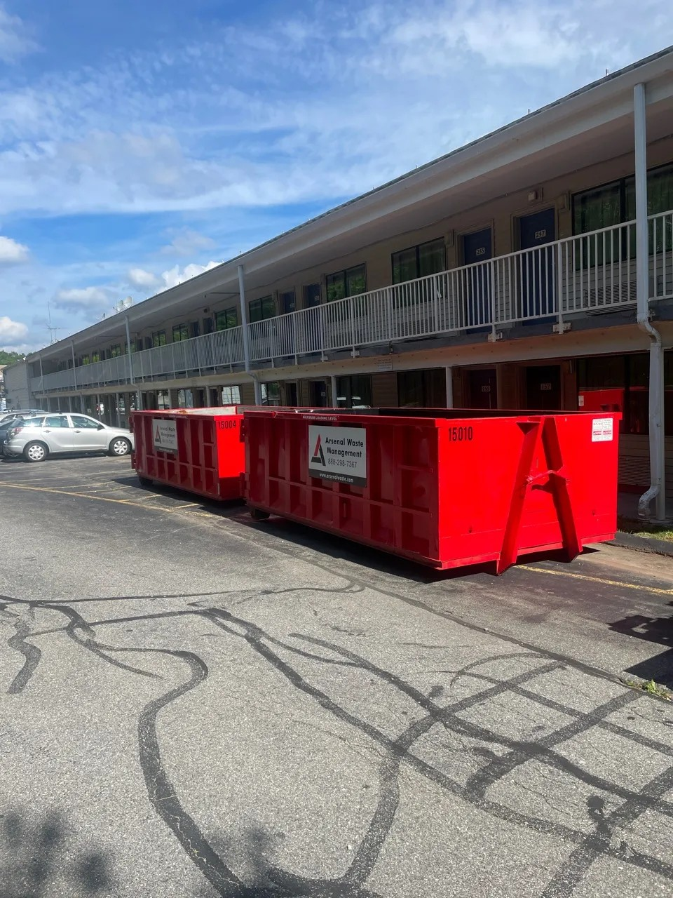 Red Arsenal roll-off dumpsters lined up beside a building