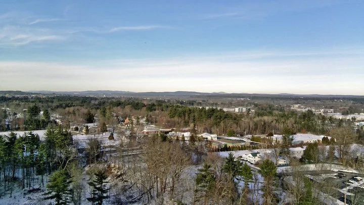 Winter aerial view of Bow village buildings and wooded surroundings, New Hampshire