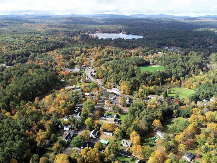 Aerial view of Brookline village, woodland and a pond in New Hampshire